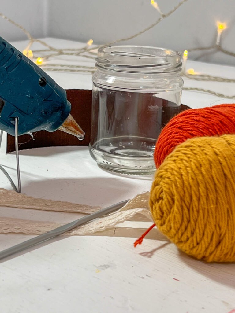 Glue gun, crochet hook, crochet yarn, glass jar and 